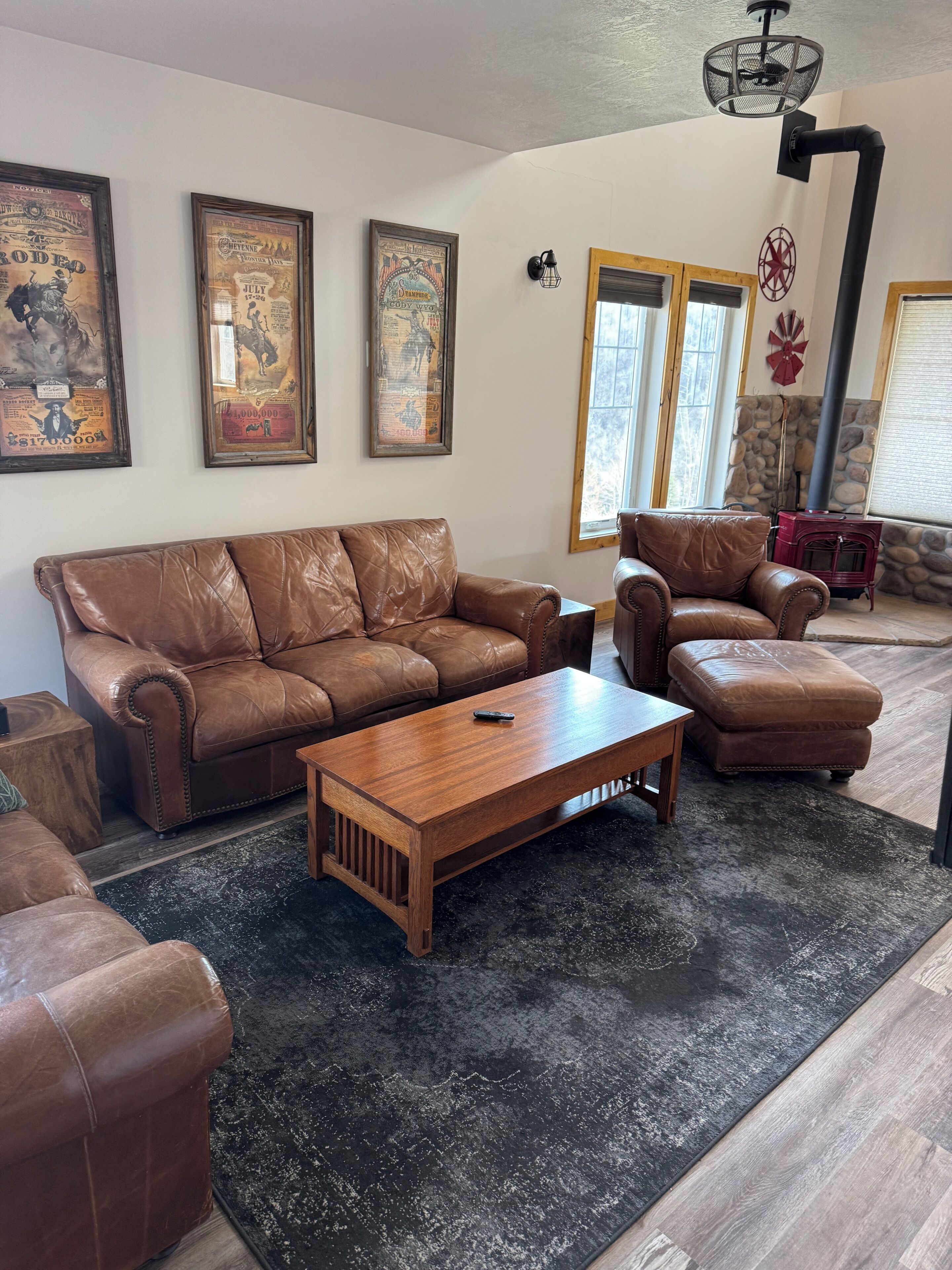A living room with a brown leather sofa, a wooden coffee table, and a red vintage stove.