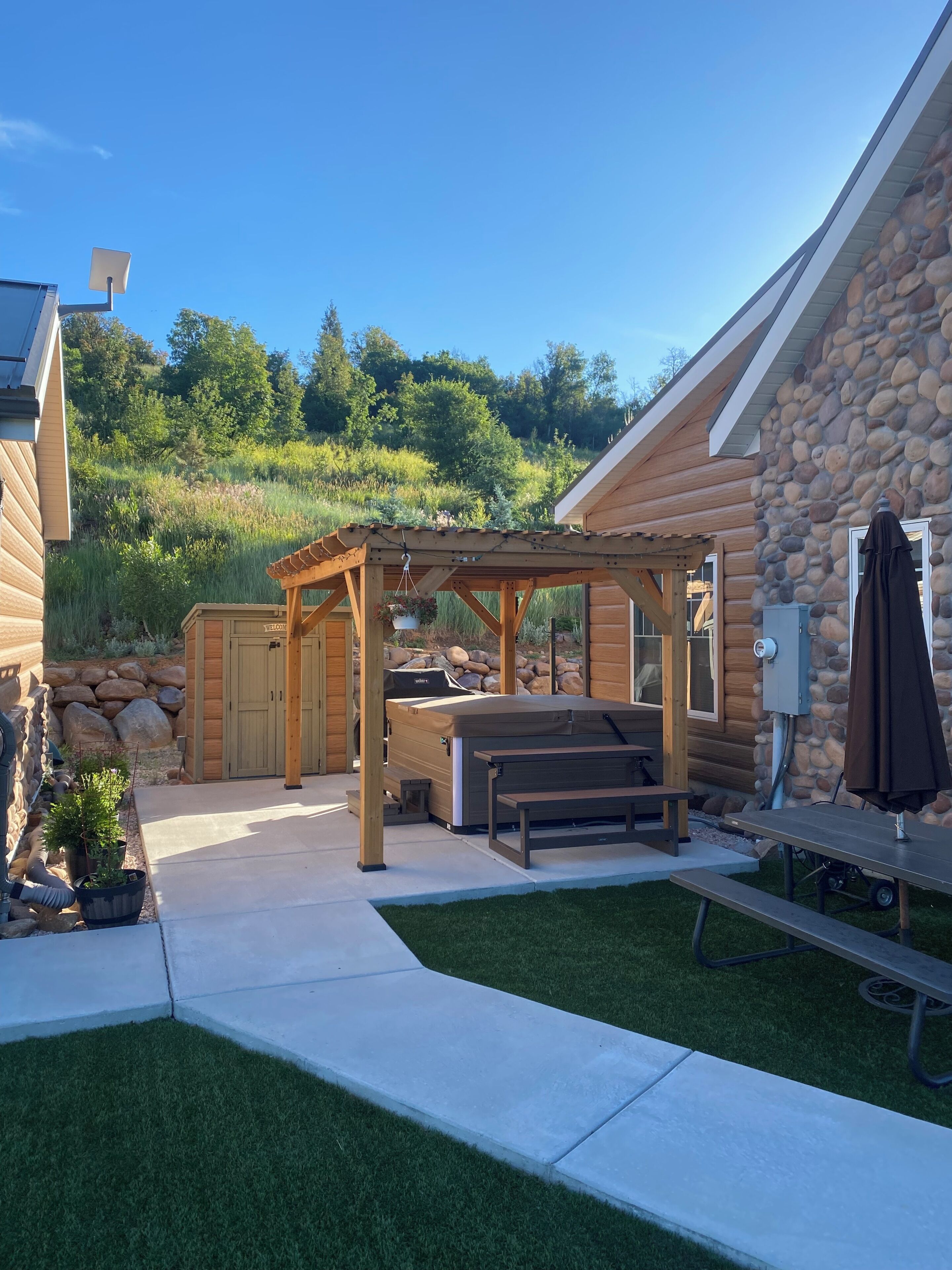 Une cabane en rondins dotée d’un jacuzzi, d’une terrasse et d’un mur en pierre.