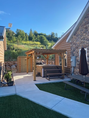 Une cabane en rondins dotée d’un jacuzzi, d’une terrasse et d’un mur en pierre.