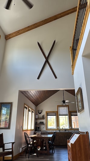 A spacious dining area with a high ceiling, wooden beams, and a large X-shaped wooden decoration.