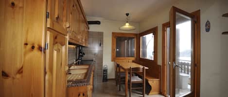 A wooden kitchen with a dining area, a sink, and a window with a view.
