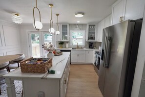 A modern kitchen with white cabinetry, a stainless steel refrigerator, and pendant lighting. - Stylish 4BR Boutique Home with Movie Lounge (Marietta)