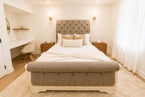 Een slaapkamer met een groot bed, nachtkastjes, een bureau en een stoel.