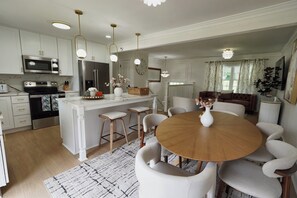 A modern kitchen with stainless steel appliances, a central island with bar stools, and pendant lighting. - Stylish 4BR Boutique Home with Movie Lounge (Marietta)