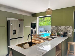 Eine moderne Küche mit einer großen Kücheninsel, Edelstahlgeräten und Blick auf einen Pool.