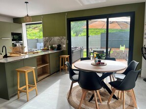 Eine moderne Küche mit Essbereich, großen Fenstern und Blick ins Freie.