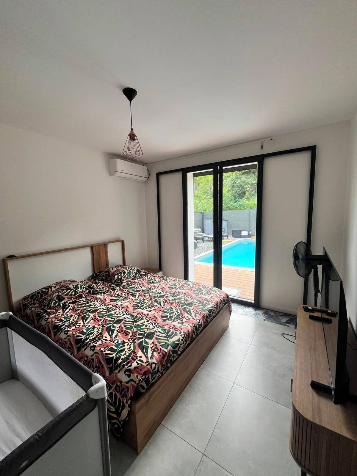 A modern bedroom with a large bed, a desk, and a view of a swimming pool.