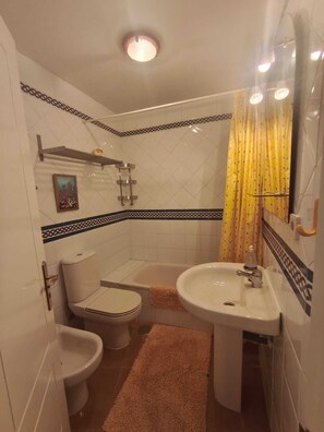 A bathroom with a toilet, bidet, bathtub, and sink. - Family Apartment in Punta del Moral (Isla Canela) (Ayamonte)