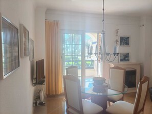 A dining area with a glass table, chairs, a television, and a fireplace. - Family Apartment in Punta del Moral (Isla Canela) (Ayamonte)