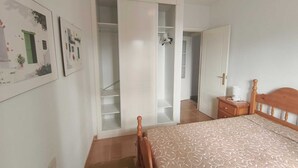 Ein Schlafzimmer mit einem Bett, einem Holzkopfende, einem Nachttisch, einem Kleiderschrank und einer Tür zu einem anderen Raum.