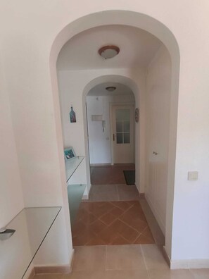 Ein Korridor mit einer gewölbten Decke, der zu einer Tür mit Fenster führt.