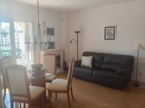 Ein Wohnzimmer mit einer schwarzen Ledersofa, einem Glastisch mit Stühlen, einem Kamin und einer Stehlampe.