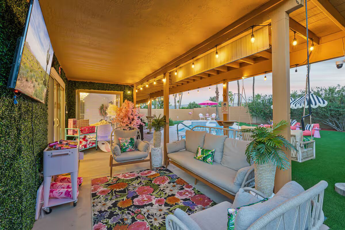 An outdoor patio with a sofa, a patterned rug, and a potted plant.