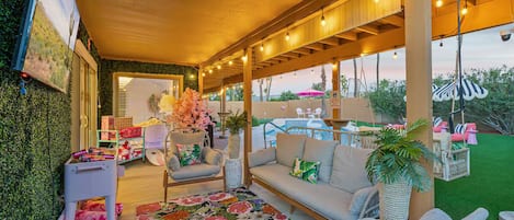 An outdoor patio with a sofa, a patterned rug, and a potted plant.