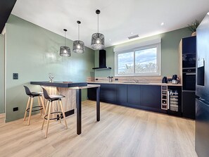 A modern kitchen with a central island, bar stools, a window with a view, and built-in appliances.