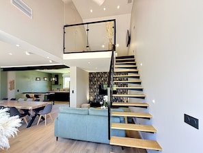A modern interior with a central staircase, a dining area, and a kitchen.