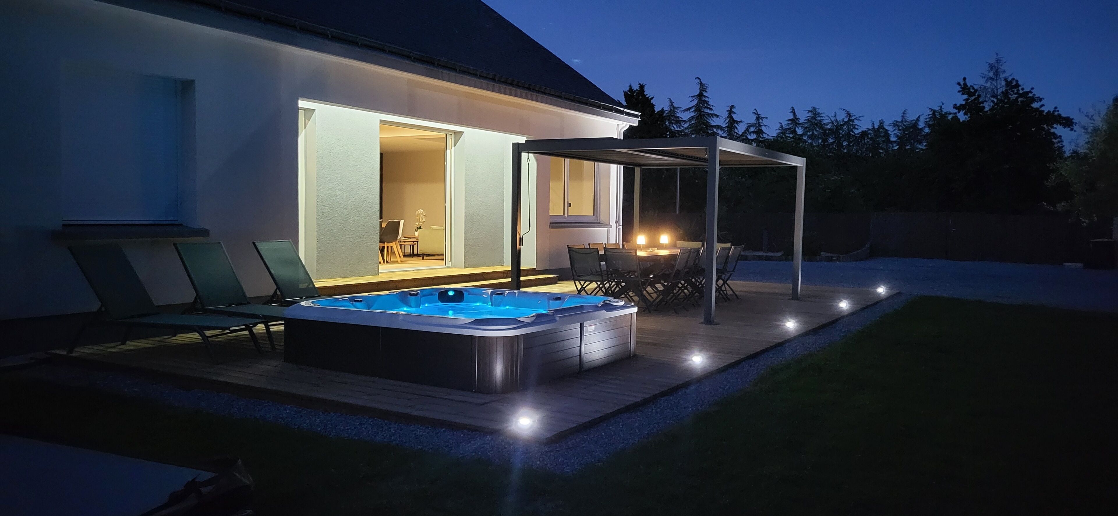 A backyard with a hot tub, outdoor seating, and a covered patio area.