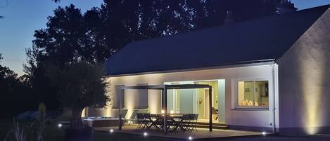 Une maison moderne dotée d’un patio, d’un espace salon extérieur et d’une grande fenêtre.