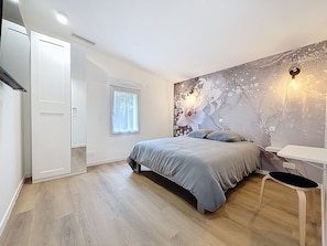 A bedroom with a bed, bedside table, and a window.