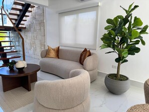 Ein modernes Wohnzimmer mit einer gebogenen Couch, einem runden Couchtisch und einer Topfpflanze.