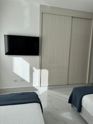 Ein Zimmer mit einem Bett, einem Kleiderschrank und einem an der Wand befestigten Flachbildfernseher.