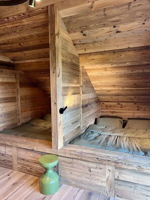 Un intérieur en bois avec un lit, un vase vert et une porte.