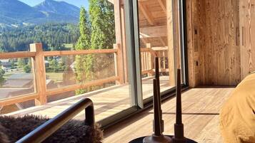 A wooden interior with a view of mountains and a balcony.