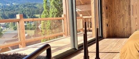 Interior de madera con vistas a montañas y un balcón.