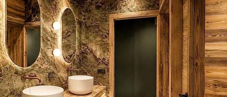 Un bagno con pareti in legno, effetto marmo, due lavabi e uno specchio con illuminazione.