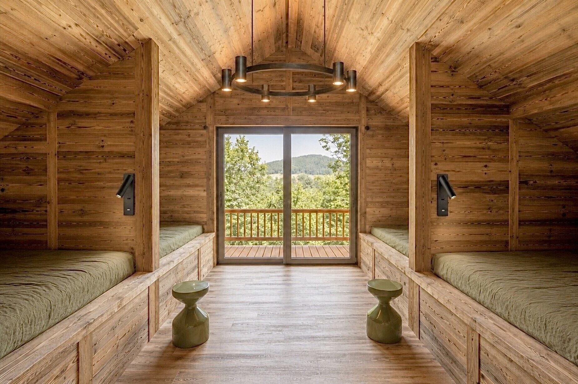 A log cabin interior with two beds, a balcony, and a view of the outdoors.