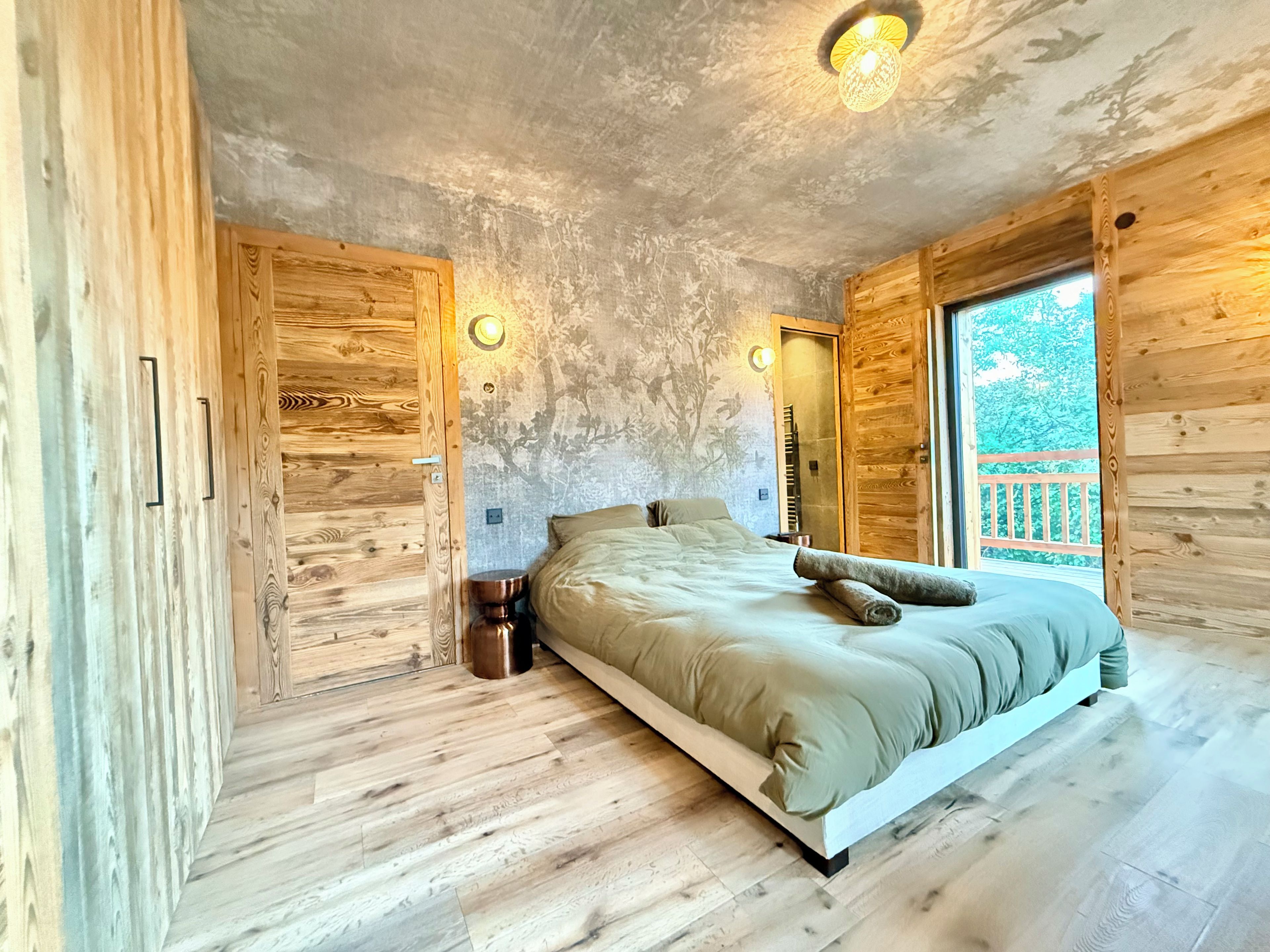 Una habitación con cama, paredes de madera y ventana con vistas.