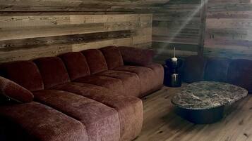 A cozy room with a wooden ceiling, a brown sofa, and a stone coffee table.
