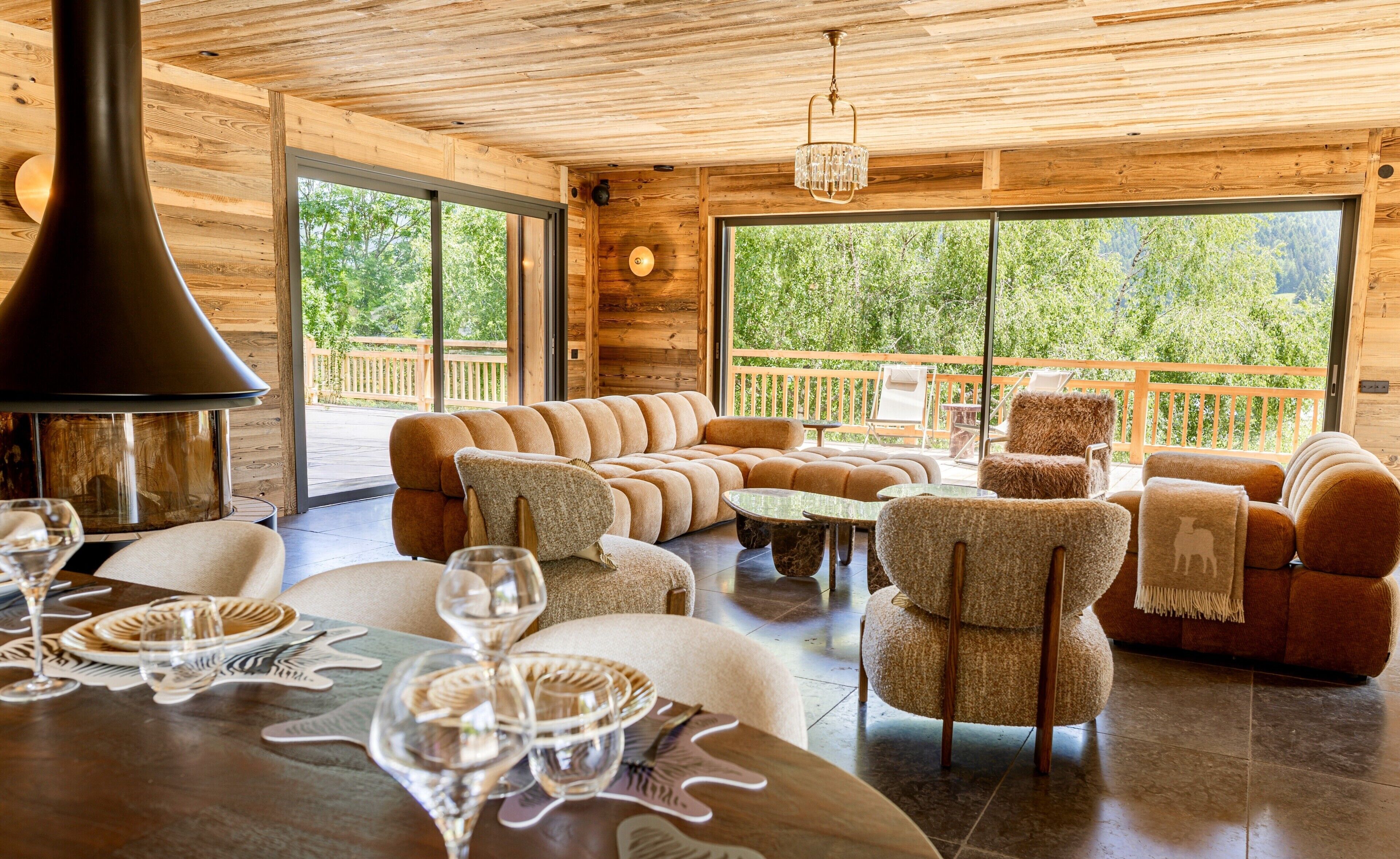 A cozy interior with a sectional sofa, armchairs, a dining table set for two, and a fireplace.