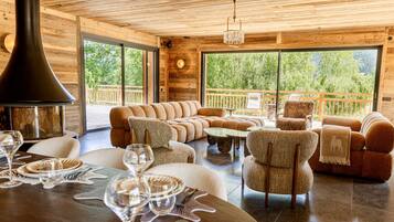 A cozy interior with a sectional sofa, armchairs, a dining table set for two, and a fireplace.