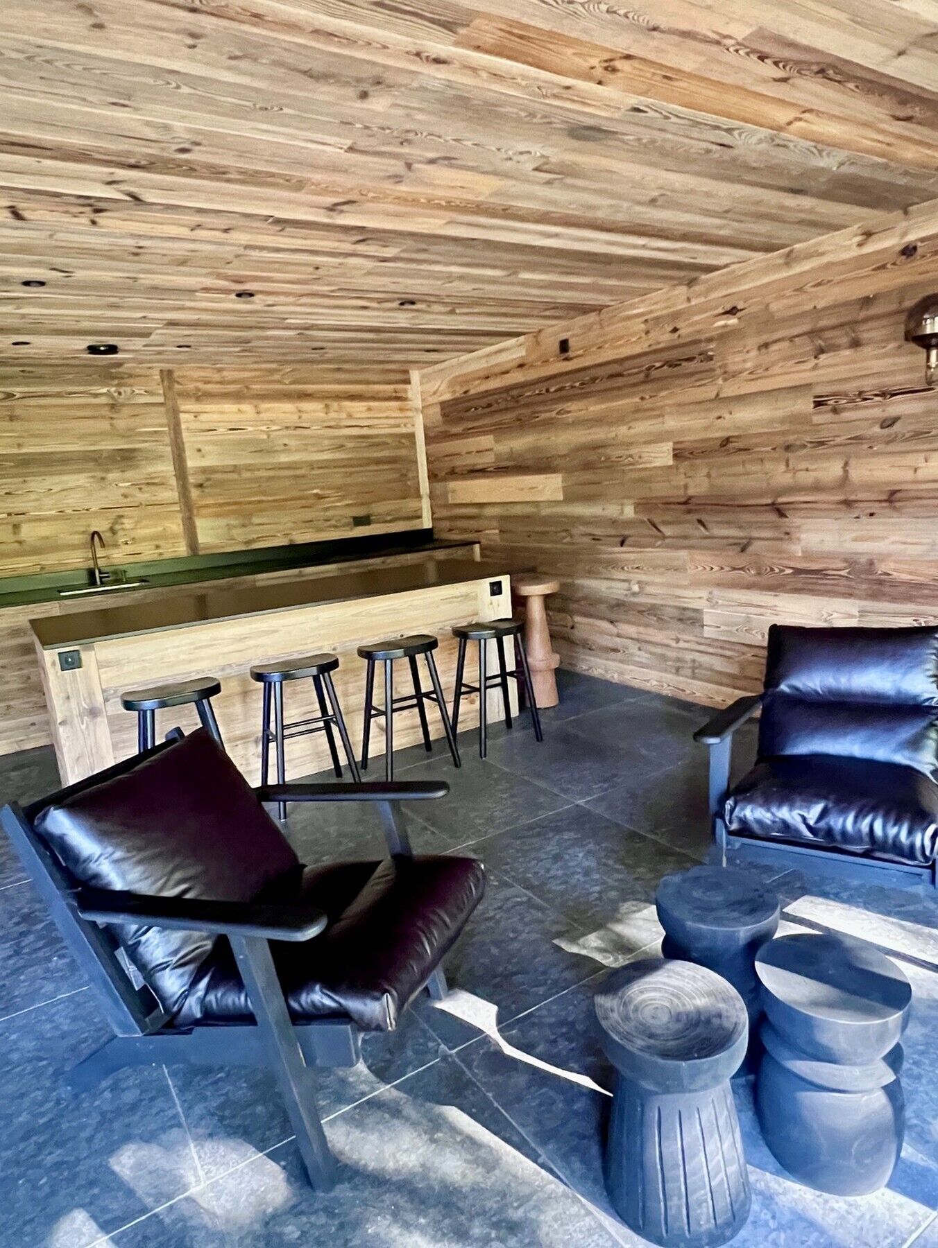 Un interior de madera con barra, asientos de cuero y piso de piedra.