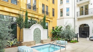 A courtyard with a swimming pool, surrounded by a yellow building and a white building.