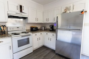 A kitchen with white cabinets, a stainless steel refrigerator, a stove, and a microwave. - Cozy room in 3 bed 2 bath house 10 minutes from Uptown CLT (Charlotte)