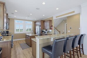 Eine moderne Küche mit Granitarbeitsplatten, Edelstahlgeräten und einer Bar mit Ledersesseln.