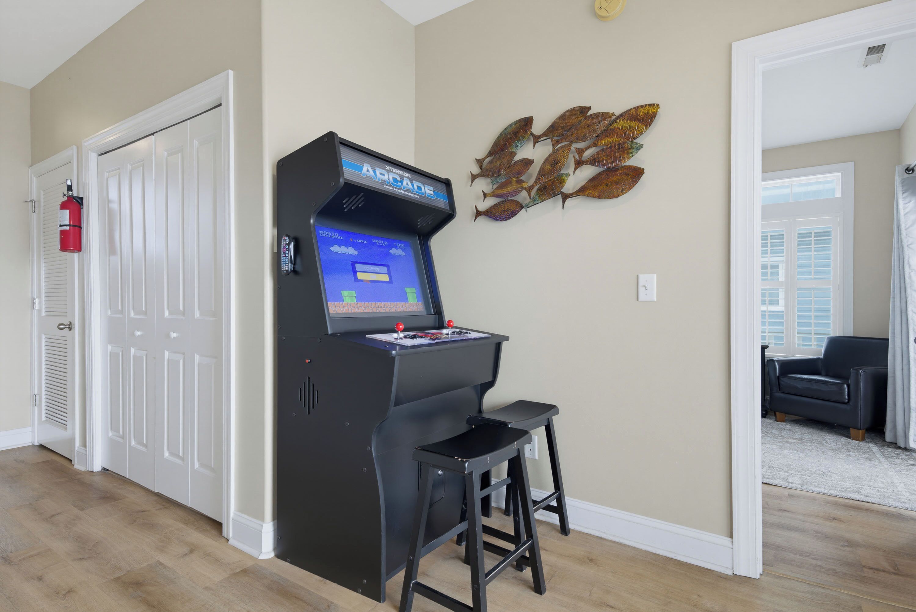 A room with a gaming console, a fire extinguisher, and a wall art piece.