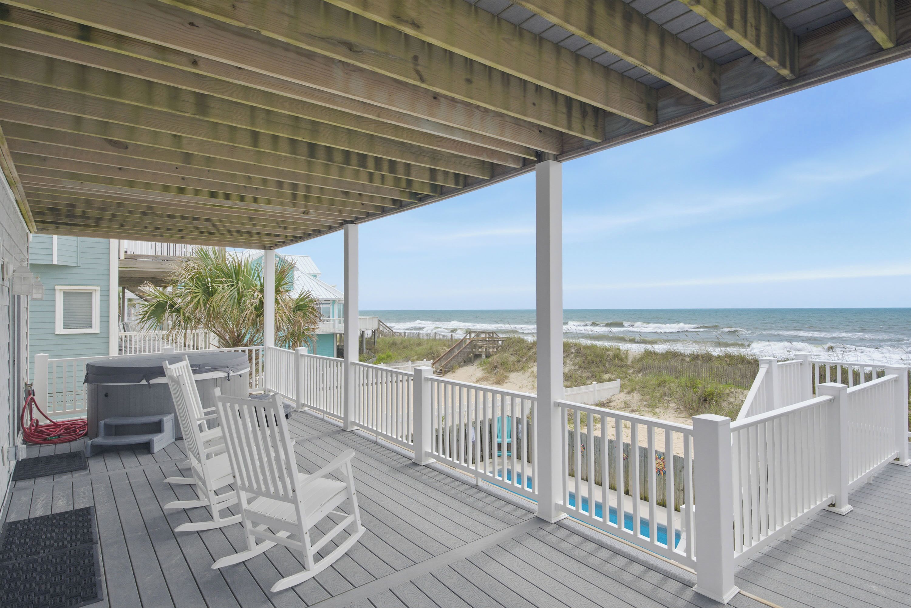 A covered deck with a view of the beach and ocean.
