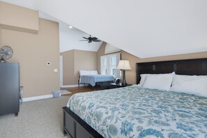 A bedroom with a large bed, a ceiling fan, a desk with a lamp, and a window with blinds. - Oceanfront pool, hot tub and game room (North Topsail Beach)