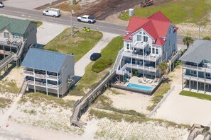 A beachfront property with multiple buildings, including a large house with a red roof and a smaller building with a blue roof. - Oceanfront pool, hot tub and game room (North Topsail Beach)