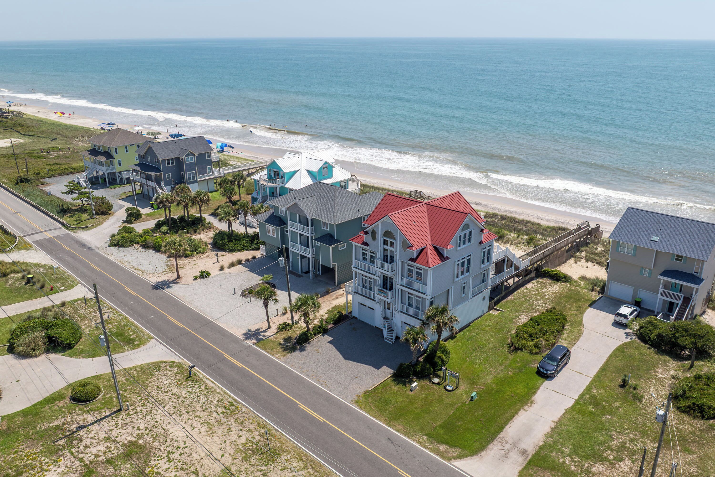 A coastal residential area with multiple houses, a beach, and a road.