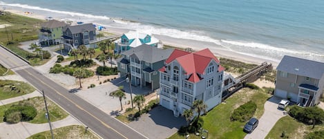 A coastal residential area with multiple houses, a beach, and a road.