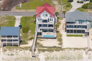 Ein Strandgrundstück mit zwei Geschossen, einem Schwimmbad, einer überdachten Terrasse und einem separaten Gebäude mit überdachter Veranda.