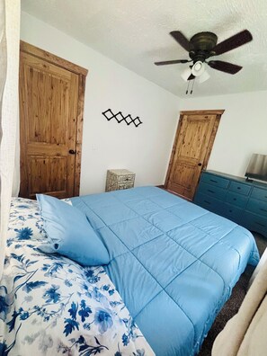 A bedroom with a bed, a ceiling fan, wooden doors, and a dresser. - 3 bedroom house in quiet Warsaw neighborhood sitting on Lake of the Ozarks! (Warsaw)