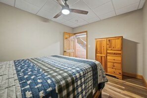 A bedroom with a bed, a ceiling fan, a wooden wardrobe, and a door leading to a staircase. - Lakefront on Winnipesaukee - Private Dock, Beach & Firepit - Sleeps 10 (Laconia)