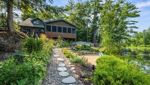 A two-story house with a stone pathway leading to the entrance. - Lakefront on Winnipesaukee - Private Dock, Beach & Firepit - Sleeps 10 (Laconia)