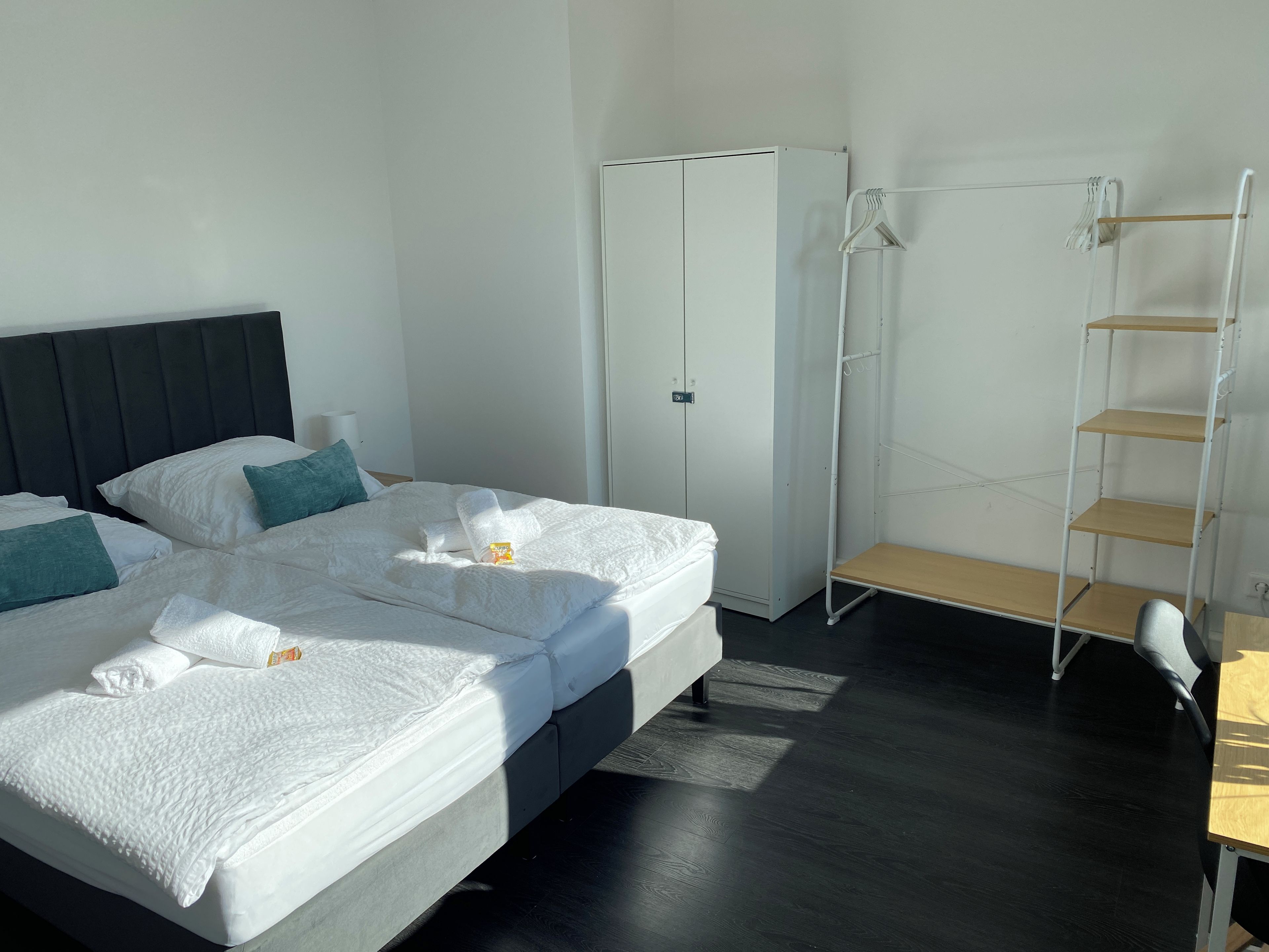 Ein Hotelzimmer mit einem Bett, einem Schrank, einer Regaleinheit und einem Schreibtisch.
