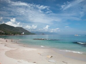 A beach with clear water, a few people, and a boat in the distance. - Private beachfront villa w/ private pool and chef (Puerto Vallarta)